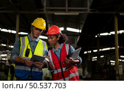 The foreign chief engineer came to inspect the old mechanical factory. There is an African female mechanic explaining details and progress reports on old machines being repaired to restore normal operation. Стоковое фото, агентство Ingram Publishing / Фотобанк Лори
