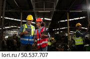 The foreign chief engineer came to inspect the old mechanical factory. There is an African female mechanic explaining details and progress reports on old machines being repaired to restore normal operation. Стоковое фото, агентство Ingram Publishing / Фотобанк Лори