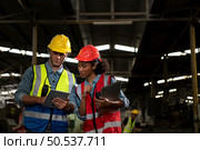 The foreign chief engineer came to inspect the old mechanical factory. There is an African female mechanic explaining details and progress reports on old machines being repaired to restore normal operation. Стоковое фото, агентство Ingram Publishing / Фотобанк Лори