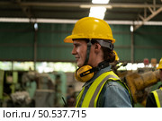 Chief mechanical engineer working in a mechanical factory make radio communication control with walkie-talkie and follow up with Asian technicians who are repairing old machines. Стоковое фото, агентство Ingram Publishing / Фотобанк Лори