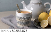 Cup of hot tea with lemon dressed in knitted warm winter scarf on wooden tabletop. Стоковое фото, агентство Ingram Publishing / Фотобанк Лори