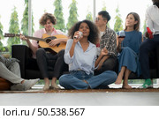Group of multiethnic friends having fun at party by playing guitar and singing together at home. Стоковое фото, агентство Ingram Publishing / Фотобанк Лори