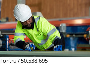 Young engineers engineers testing and confirming that the machinery at the factory that creates metal sheet tiles is functioning as intended. Стоковое фото, агентство Ingram Publishing / Фотобанк Лори