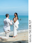 A young white man Asking for an Asian girl to marry with a diamond ring on a beach as beautiful as heaven. Стоковое фото, агентство Ingram Publishing / Фотобанк Лори