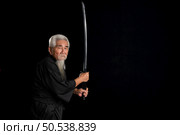 Senior Japanese samurai with katana sword on black background, studio shot. Стоковое фото, агентство Ingram Publishing / Фотобанк Лори