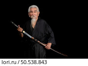 Senior Japanese samurai with katana sword on black background, studio shot. Стоковое фото, агентство Ingram Publishing / Фотобанк Лори