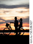 Little girls riding bicycles in the early morning light of the day while the sun beams a stunning shade of orange. Стоковое фото, агентство Ingram Publishing / Фотобанк Лори