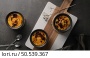 Creme brulee. Bowls with French vanilla cream dessert with caramelised sugar on top, spoons, dark rustic table. Стоковое фото, агентство Ingram Publishing / Фотобанк Лори