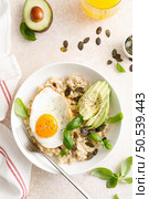 Savory oatmeal with fried sunny side up egg, avocado and pumpkin seeds for healthy breakfast. Стоковое фото, агентство Ingram Publishing / Фотобанк Лори
