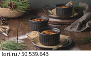 Creme brulee. Bowls with French vanilla cream dessert with caramelised sugar on top, spoons, dark rustic table. Стоковое фото, агентство Ingram Publishing / Фотобанк Лори