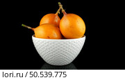 Passion fruit maracuja granadilla on ceramic white bowl, black background. Стоковое фото, агентство Ingram Publishing / Фотобанк Лори
