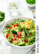 Couscous salad with broccoli, green peas, tomatoes, avocado and fresh arugula. Healthy natural plant based vegetarian food for lunch, israeli cuisine. Стоковое фото, агентство Ingram Publishing / Фотобанк Лори