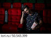 Man falls asleep while watching movie in cinema and popcorn in hand, Movie lacking interesting and boring. Стоковое фото, агентство Ingram Publishing / Фотобанк Лори