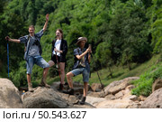 Young man hiker with backpack and trekking poles with a young man helping to pull him up to stand on the rock. Стоковое фото, агентство Ingram Publishing / Фотобанк Лори