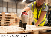Young workers working in a woodworking factory, Using a nailing machine to assemble wooden pallets. Стоковое фото, агентство Ingram Publishing / Фотобанк Лори