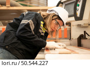Young woman worker work in a woodworking factory, Working with wood sawing and cutting machines to produce wooden sheets for making pallets. Стоковое фото, агентство Ingram Publishing / Фотобанк Лори