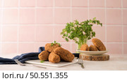 Cod dumplings, or "bolinhos de bacalhau" and parsley leaves on white ceramic dishes in a kitchen counter top. Стоковое фото, агентство Ingram Publishing / Фотобанк Лори