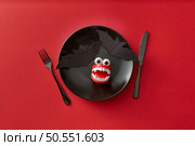A black plate with a bat and vampire teeth on it, on a red background. A knife and fork on each side add to the horror theme. A perfect plate setting for a Halloween meal. Стоковое фото, агентство Ingram Publishing / Фотобанк Лори