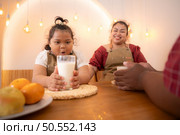 A plus-size family with a father wearing a prosthetic leg, Eat together after cooking and daughter drinks milk for health in the dining room of the house. Стоковое фото, агентство Ingram Publishing / Фотобанк Лори