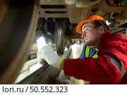 Two engineers for electric trains After detecting difficulties with the electric train’s machinery use searchlights to locate and check damaged sections. In the electric train repair shop. Стоковое фото, агентство Ingram Publishing / Фотобанк Лори