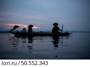 Silhouette of fisherman at sunrise, Standing aboard a rowing boat and casting a net to catch fish for food. Стоковое фото, агентство Ingram Publishing / Фотобанк Лори