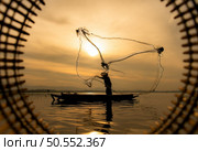 Silhouette of fisherman at sunrise, Standing aboard a rowing boat and casting a net to catch fish for food. Стоковое фото, агентство Ingram Publishing / Фотобанк Лори