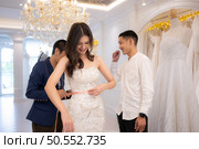 Bridal gown designers and tailors measure the size of the gown against the bride’s figure when she comes to try on the gown in order to make it perfect and ready to wear on the wedding day. Стоковое фото, агентство Ingram Publishing / Фотобанк Лори