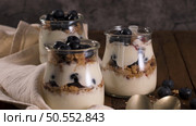 Yogurt parfait with blueberry and granola. Healthy breakfast concept served in mason jar with decorative spoons on wooden table. Стоковое фото, агентство Ingram Publishing / Фотобанк Лори