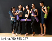 Yoga class of young people interested in yoga activities With a yoga teacher who helps teach yoga postures to students In order to be physically strong and flexible. Стоковое фото, агентство Ingram Publishing / Фотобанк Лори