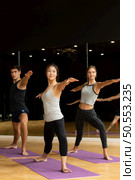 Yoga class of young people interested in yoga activities With a yoga teacher who helps teach yoga postures to students In order to be physically strong and flexible. Стоковое фото, агентство Ingram Publishing / Фотобанк Лори