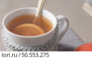 Cup of hot tea with lemon dressed in knitted warm winter scarf on wooden tabletop. Стоковое фото, агентство Ingram Publishing / Фотобанк Лори