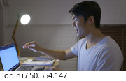 When the laptop was turned on, a young Asian man working overtime at home received good news regarding the project he worked on. Стоковое фото, агентство Ingram Publishing / Фотобанк Лори