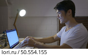 When the laptop was turned on, a young Asian man working overtime at home received good news regarding the project he worked on. Стоковое фото, агентство Ingram Publishing / Фотобанк Лори