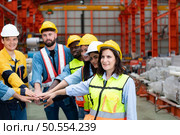 Group of factory workers in hardhats with joint hands together for celebrating success. Стоковое фото, агентство Ingram Publishing / Фотобанк Лори