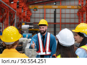 Supervisor and group of factory workers wearing hard hats meeting brief together before starting the day’s work. Стоковое фото, агентство Ingram Publishing / Фотобанк Лори