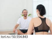 Young female and male athletes sitting rest on yoga mats and drinking water. They are looking at each other and smiling. Стоковое фото, агентство Ingram Publishing / Фотобанк Лори