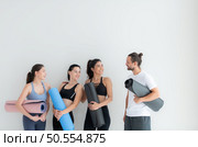 A group of female and male athletes stood and chatted amicably in the studio before beginning with the yoga class. Стоковое фото, агентство Ingram Publishing / Фотобанк Лори