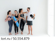 A group of female and male athletes stood and chatted amicably in the studio before beginning with the yoga class. Стоковое фото, агентство Ingram Publishing / Фотобанк Лори