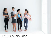 A group of female and male athletes stood and chatted amicably in the studio before beginning with the yoga class. Стоковое фото, агентство Ingram Publishing / Фотобанк Лори