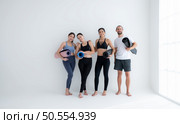 A group of female and male athletes stood and chatted amicably in the studio before beginning with the yoga class. Стоковое фото, агентство Ingram Publishing / Фотобанк Лори