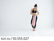 Full length portrait of a young woman holding yoga mat isolated on white background. Стоковое фото, агентство Ingram Publishing / Фотобанк Лори