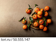 Mandarin oranges, clementines or tangerines with leaves on a dark background, top view. Стоковое фото, агентство Ingram Publishing / Фотобанк Лори