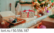 A lot of packing handmade gift boxes lying on the table near Christmas tree in the midst of golden lights, glowing garland, candle. Soft focus. Стоковое фото, агентство Ingram Publishing / Фотобанк Лори
