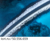Aerial view of snowy road to the island and blue sea on both side. Bridge on snow and azure transparent water in winter. Landscape. Top drone view of road to the Henningsvaer, Lofoten islands, Norway. Стоковое фото, агентство Ingram Publishing / Фотобанк Лори