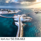 Aerial view of road and bridges, snowy rocks, islands with rorbu, sea, water, mountains, cloudy sky at sunset in winter. Beautiful north landscape. Top view of Henningsvaer, Lofoten islands, Norway. Стоковое фото, агентство Ingram Publishing / Фотобанк Лори
