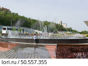 Высокие струи воды в фонтане на берегу реки Волги, счастливый ребёнок возле фонтана в жаркий день. Волгоград, Центральная набережная, Россия. Редакционное фото, фотограф Андрей Цыганков / Фотобанк Лори