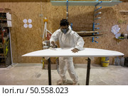 Surfboard manufacturing, Shaper working on board details. Concept of industrial manufacturing, qualified professional, occupation and employment. Стоковое фото, агентство Ingram Publishing / Фотобанк Лори