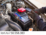 A man wearing gloves securely fastens a car battery terminal after installing it under the hood. Replacing a weak battery. Стоковое фото, фотограф Коханова Наталья / Фотобанк Лори