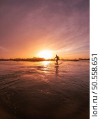 Hydrofoil rider gliding over the water with his board in one of the canals of the Ria de Aveiro in Portugal during sunset. Стоковое фото, агентство Ingram Publishing / Фотобанк Лори
