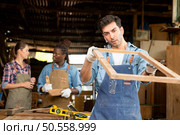 Portrait of carpenter male worker standing in front of colleague in workshop, Eyesight is utilized to ensure accuracy. Стоковое фото, агентство Ingram Publishing / Фотобанк Лори